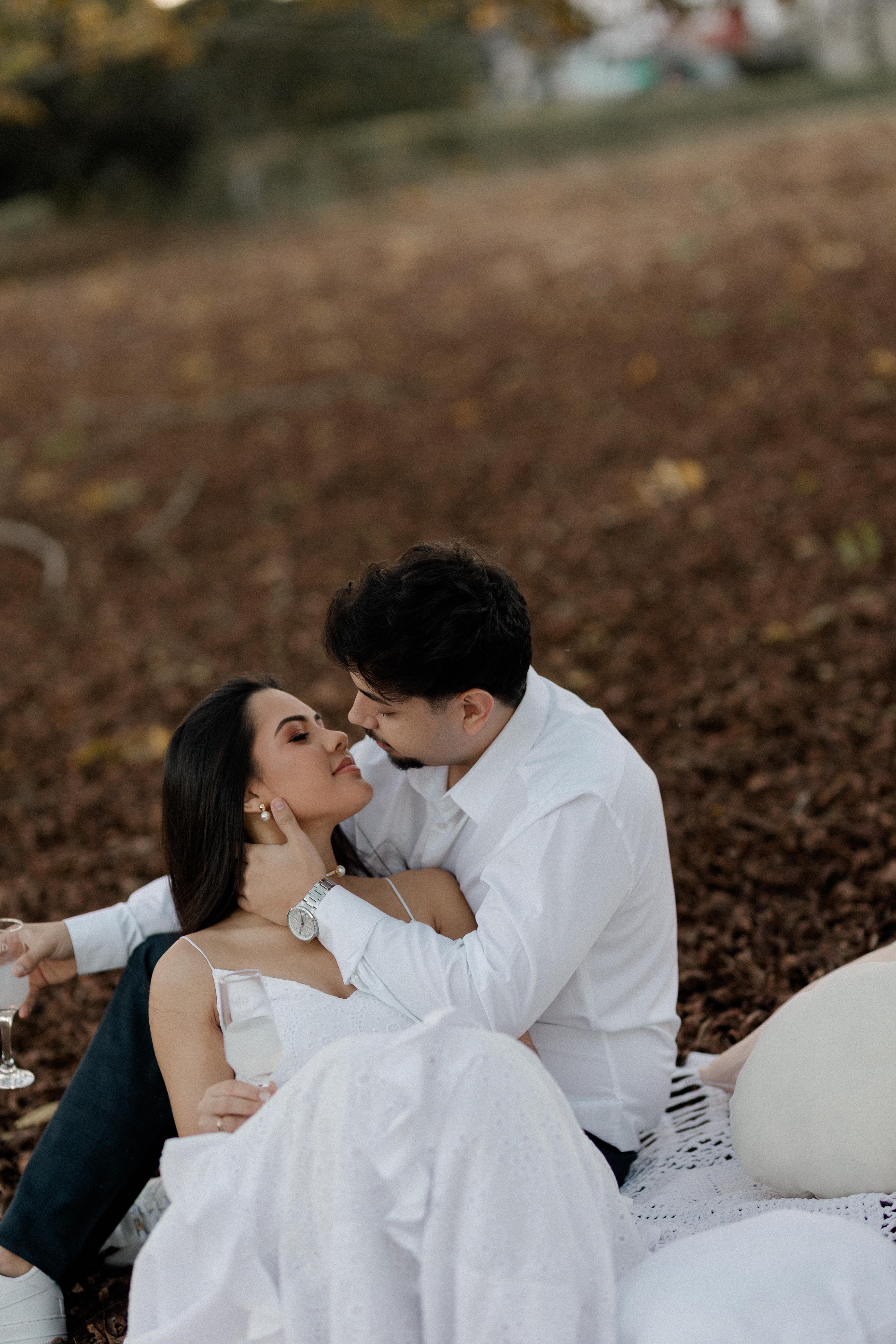 Casal sentado nas folhas de outono em momento romântico